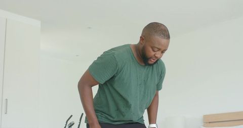African american man catching breath after intense cardio workout, perspiring and focusing