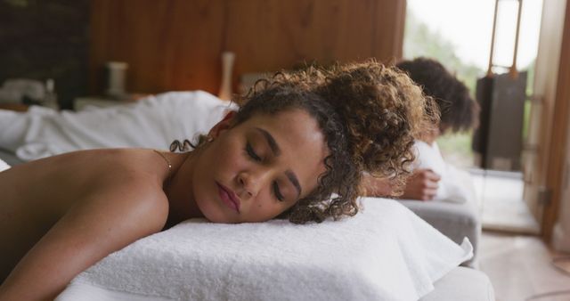 Image of relaxed diverse couple lying with eyes closed on massage tables at health spa. Vacation, togetherness, relaxation, health, happiness and inclusivity concept.
