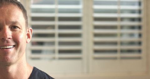 Senior Man Smiling at Home with Plantation Shutters