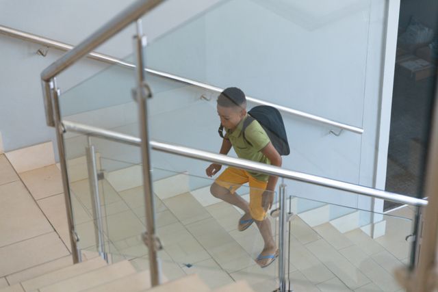 High angle view of african american elementary schoolboy climbing steps in school building. unaltered, childhood, education and school concept.