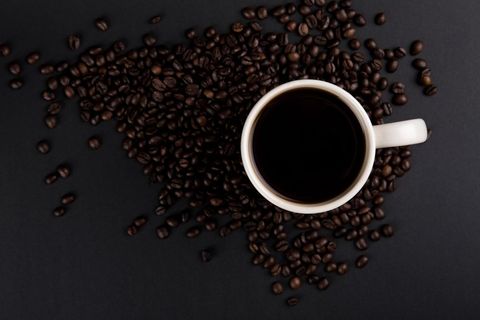 Coffee Cup Surrounded by Beans on Dark Surface