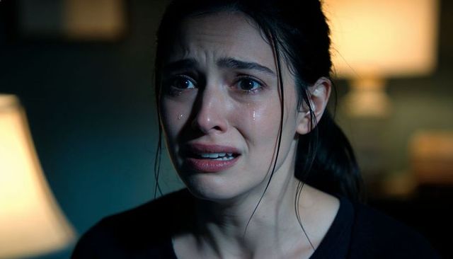 Crying adult woman shedding tears in dim living room with warm lamp backlight, emotional closeup por