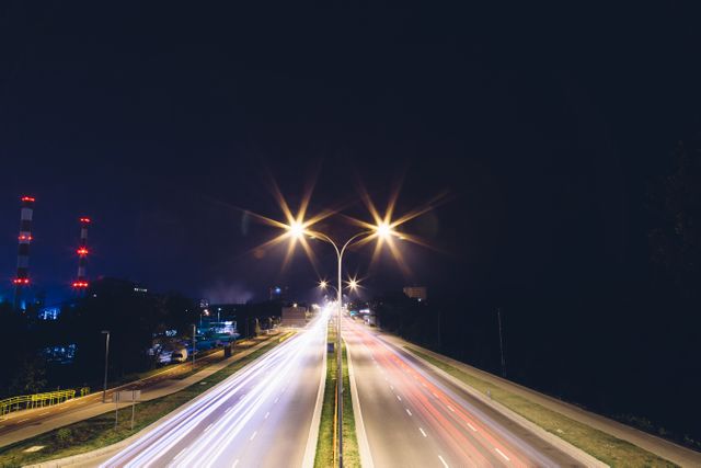Highway scene at night capturing motion blur from fast-moving traffic under bright street lights. Long exposure adds dynamic light trails, perfect for projects related to urban life, transportation, speed, city nightlife, and travel imagery.