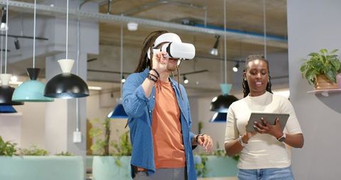 African American team testing VR headset while collaborating with tablet in coworking hub