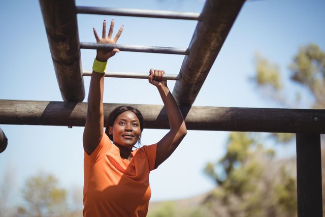 Determined woman exercising on monkey bar during obstacle course in boot camp