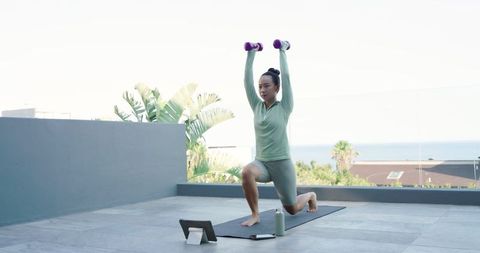 Young Woman Performing Dumbbell Lunges on Rooftop Terrace