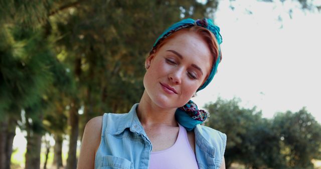 Young woman enjoying calm moment in outdoor natural setting, eyes closed with relaxed smile. Suitable for themes about mindfulness, relaxation, connecting with nature, and mental wellness. Ideal for wellness blogs, nature retreat promotions, and social media campaigns related to peace and tranquility.