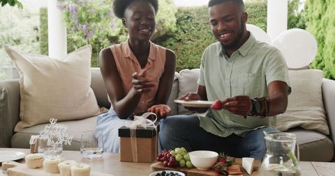 Couple celebrating anniversary with gifts and fruit platter