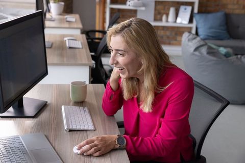 Cheerful Professional Woman Engaging with Modern Technology at Office Desk