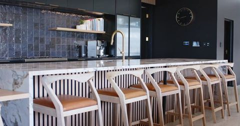 Marble island featuring light wood stools and brass faucet in modern open plan kitchen