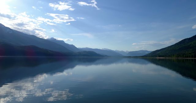 A serene lake reflects the surrounding mountains under a clear blue sky, with copy space. The tranquil setting evokes a sense of peace and the beauty of untouched nature.