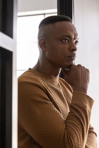 Pensive man in brown quilted shirt gazing out window