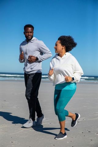 Couple Jogging Along Beach in Athletic Wear with Fitness Trackers