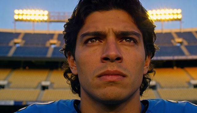 Focused young football player gazing upward in stadium at golden hour closeup