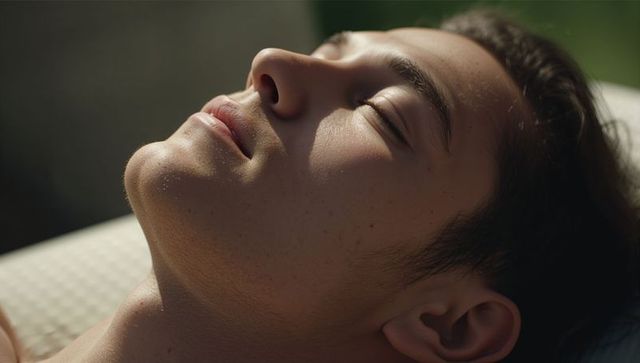 Reclining asian man relaxing with closed eyes and sunlit skin closeup profile, serene
