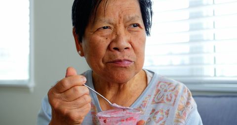 Asian Senior Woman Eating Homemade Yoghurt at Home