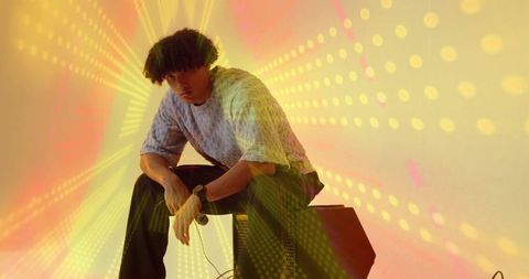 Musician Posing with Amplifier, Surrounded by Vibrant Studio Lights