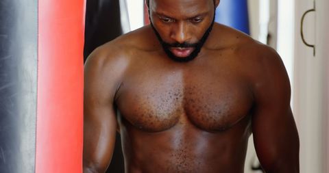 Determined Boxer Training with Punching Bag in Gym