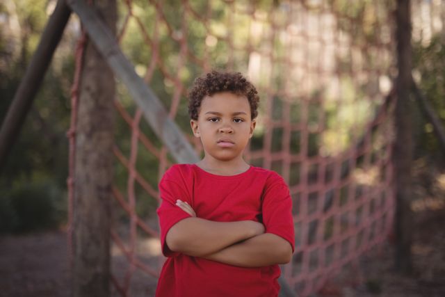 Portrait of boy standing with arms crossed during obstacle course in boot camp