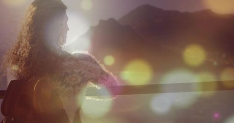 Woman observing sunrise over mountains with dreamy light