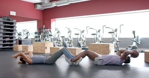 Fit Diverse Couple Partnering for Core Exercises at Gym
