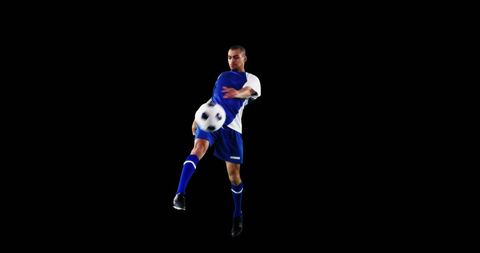 Focused Soccer Player Kicking Ball on Black Background