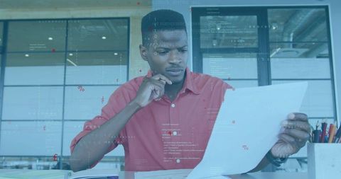 Man Reading Document at Modern Office Desk, Holding Paper and Analyzing Data Overlays