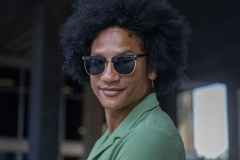 Stylish african man wearing sunglasses and nose ring posing over shoulder urban portrait