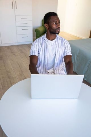 Young professional working on laptop in minimalist bedroom setup