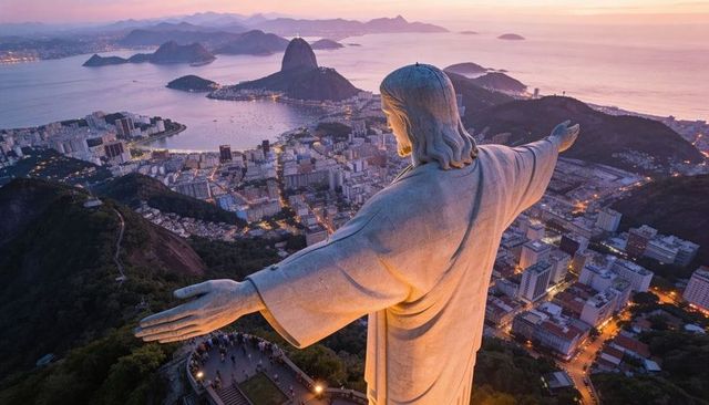 Christ redeemer overlooking rio de janeiro sunset bay with sugarloaf mountain panoramic view
