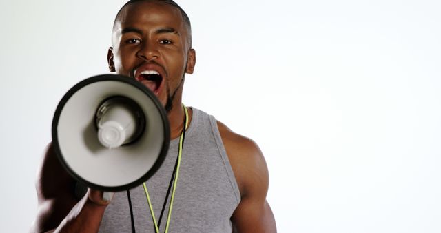 An African American man is energetically speaking into a megaphone, with copy space. His expression and the use of the megaphone suggest he is making an important announcement or rallying a crowd.