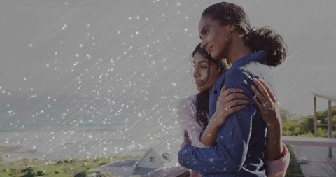 Mother and Daughter Embracing on Balcony Overlooking Serene Coast