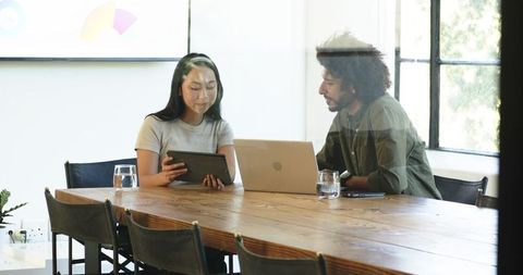 Diverse professionals meeting with tablets and laptops in office