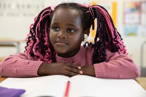 Focused young student at school desk wearing earbud studying