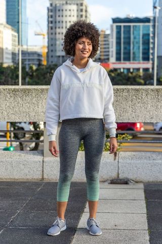 Confident urban woman checking smartwatch in hoodie and leggings for outdoor workout