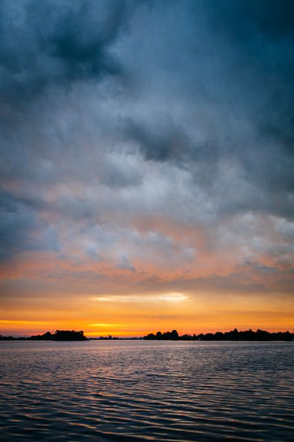 Dramatic Sunset over Calm Lake with Colorful Clouds - Download Free Stock Photos Pikwizard.com