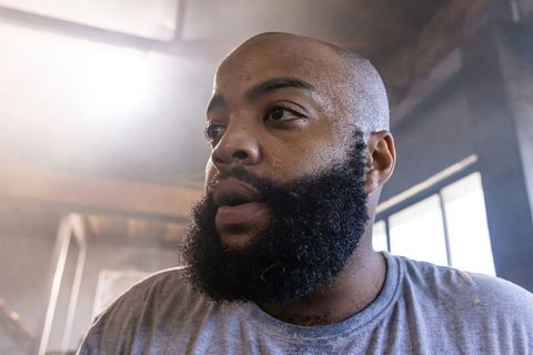 African american man breathing heavily after intense workout in industrial gym with backlit haze