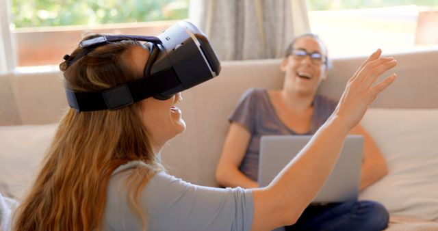 Woman Using Virtual Reality Headset with Friend Laughing on Sofa - Download Free Stock Images Pikwizard.com
