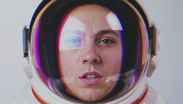 Female astronaut wearing reflective visor and futuristic spacesuit closeup headshot with intense gaz