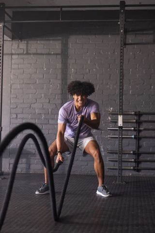 Man performing battle rope workout building strength and endurance in gym
