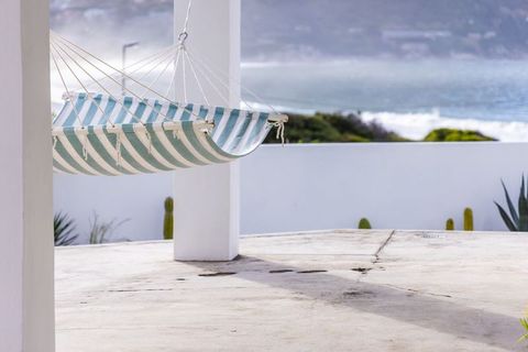 Striped hammock hanging from white post overlooking calm coastal ocean view