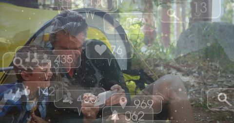 Parent sharing smartphone with child in tent on camping trip showing social media overlays