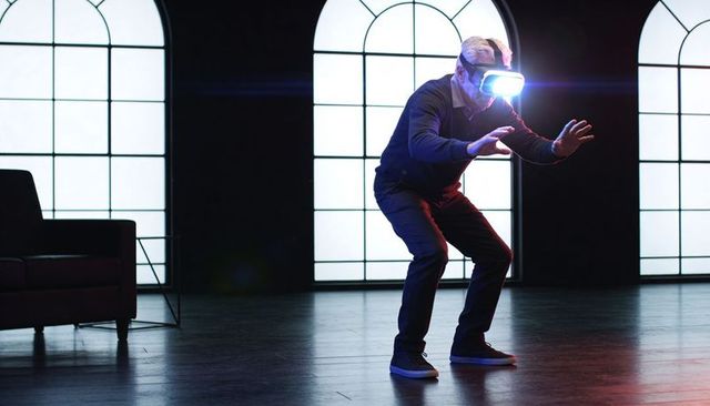 Senior Man Reaching While Wearing Glowing VR Headset in Dramatic Backlit Interior