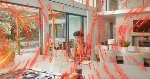 Young man working on laptop at kitchen island with coffee, open-plan living and patio view