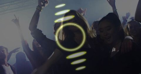 Central woman dancing under neon swirl and haze on crowded nightclub dancefloor