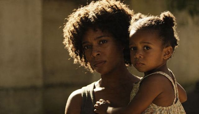 Sunlit mother cradling toddler outdoors showing protective bond, tender care and quiet mood