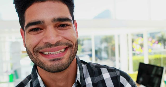 Smiling Man with Beard in Checkered Shirt, Bright Office Background - Download Free Stock Images Pikwizard.com