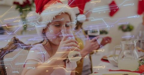 Child wearing santa hat drinking milk at festive table with futuristic circuit overlay