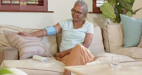 Senior woman monitoring blood pressure at home using digital device