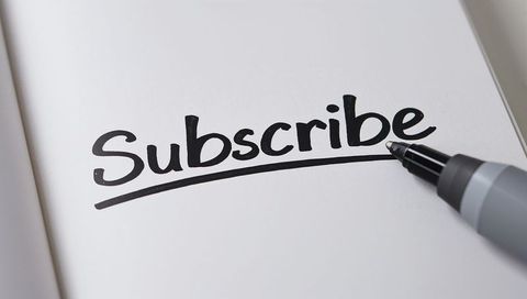 Writing subscribe lettering with black marker and underline on white page close-up minimal